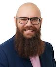 A bald man wearing glasses with a beard smiling and looking at the camera.